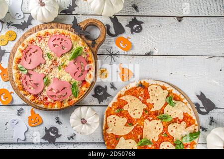 Verschiedene Halloween lustige Pizza. Halloween Party Rezept, Kreative Idee für Halloween Pizza`s mit Schinken und Käse Geister, Monster, Spinnen, weiß Holz Stockfoto